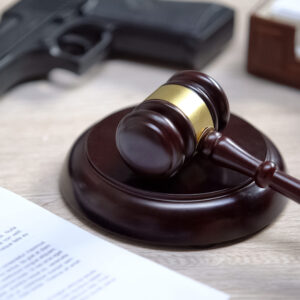 Gavel, hand gun, and legal document on a table