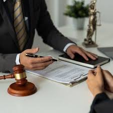 Lawyer reviewing contract documents with a client at a desk, with legal paperwork, law book, and judge&rsquo;s gavel, representing professional legal advice and agreement signing