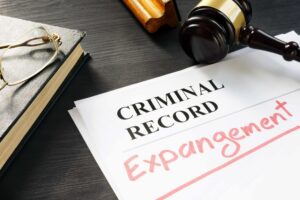 Criminal record expungement document on a desk with a judge&rsquo;s gavel and law book, representing clearing a criminal record and legal expungement services.