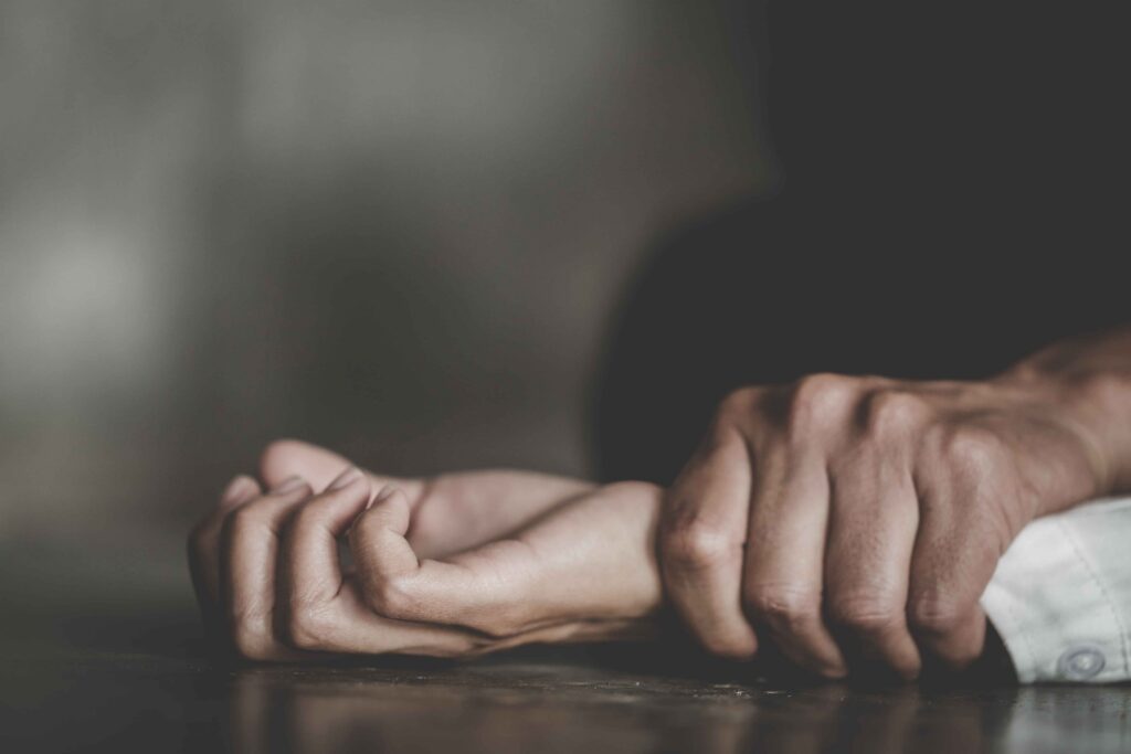 Close-up of a person holding another&rsquo;s wrist, symbolizing domestic violence, physical abuse, and the need for legal protection and restraining orders.