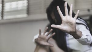 Woman holding up her hand in fear to stop abuse, representing domestic violence, victim protection, and restraining order legal support