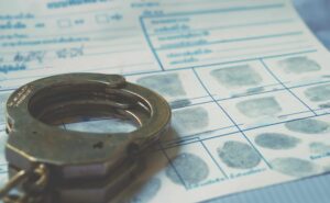Handcuffs resting on a fingerprint record card, symbolizing criminal investigation, arrest records, and law enforcement evidence