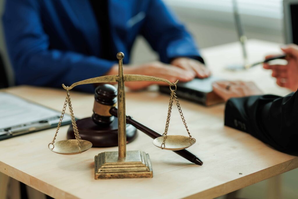 Scales of justice and judge&rsquo;s gavel on a desk during a legal consultation, symbolizing law firm services and courtroom representation.